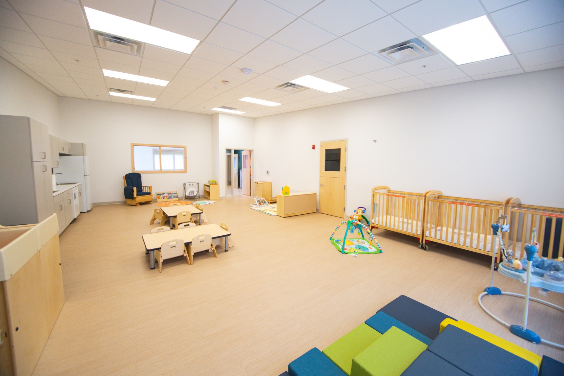 Spacious daycare classroom with cribs and play area
