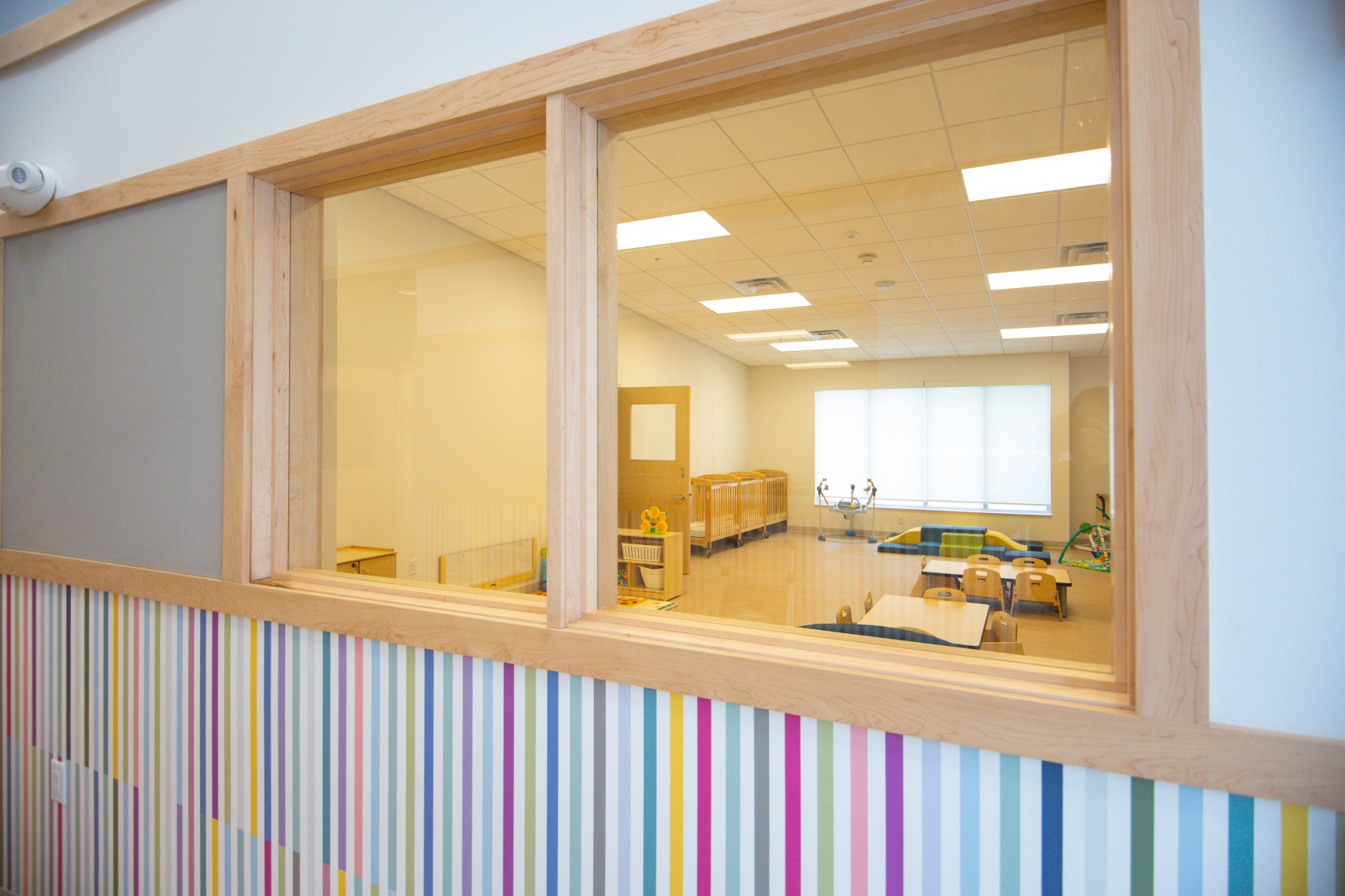 Daycare classroom with cribs, tables, and toys
