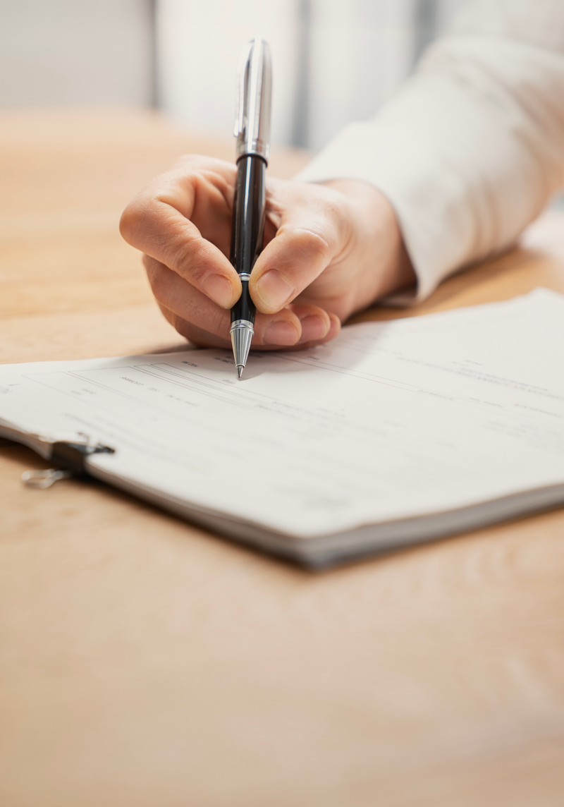 Hand signing document with pen on clipboard