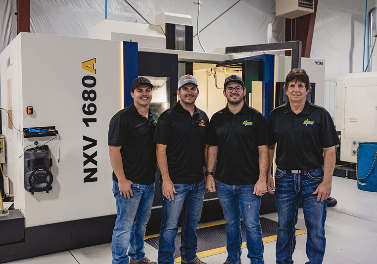 Four workers standing before large NXV 1680 machine