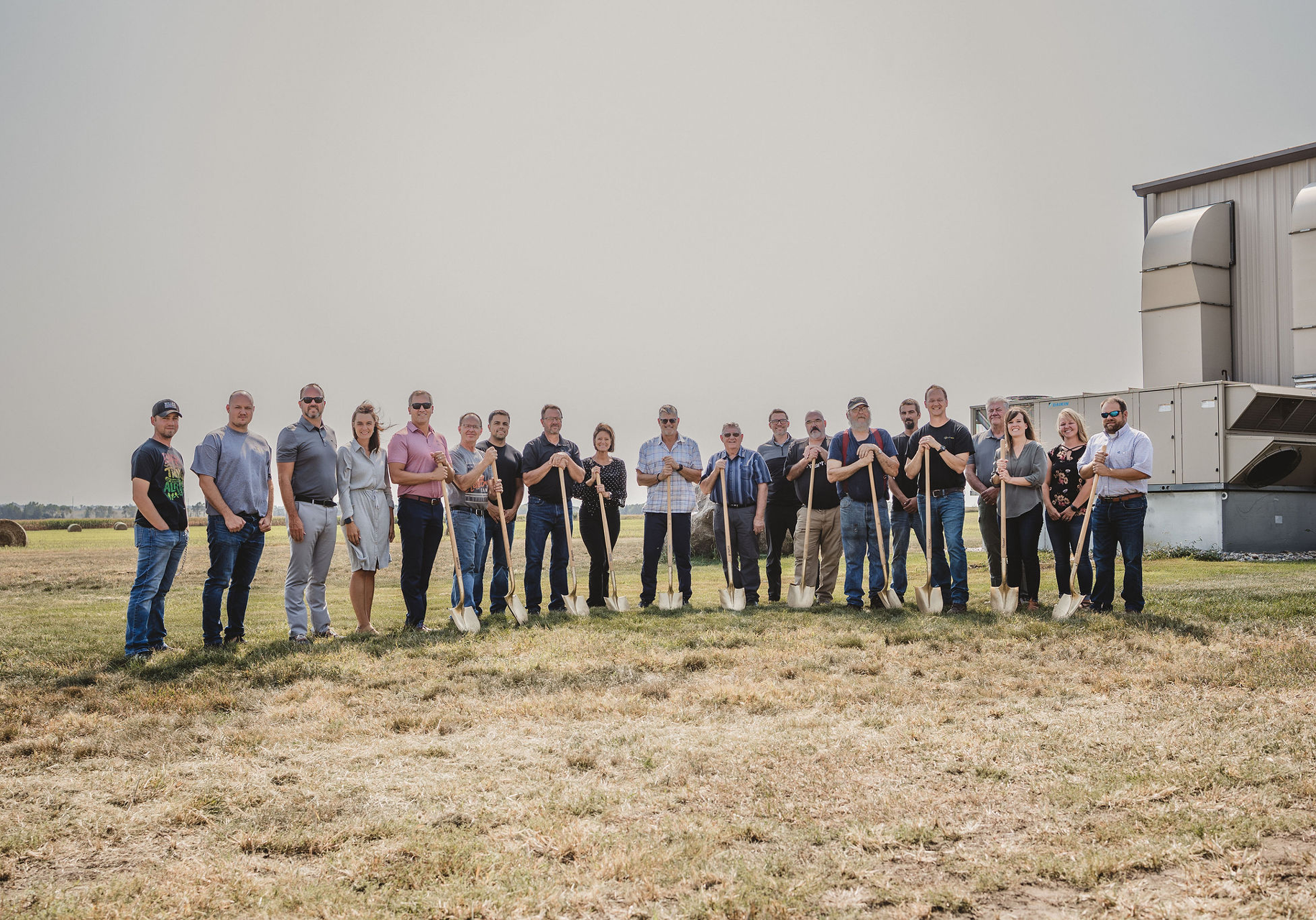 Group holding shovels at groundbreaking ceremony outdoors