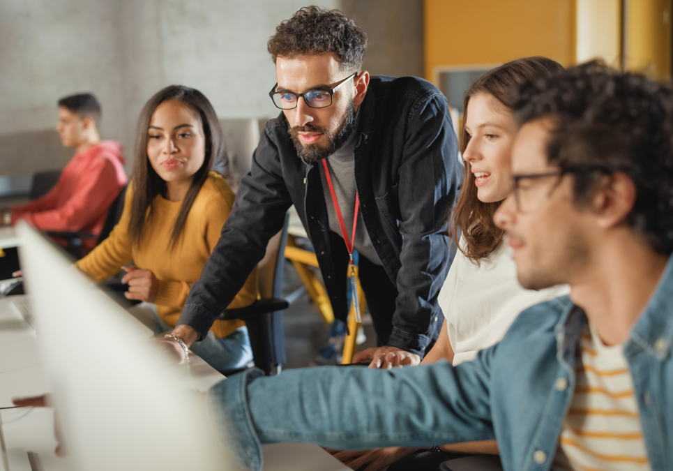 Team collaborating at computers in modern office